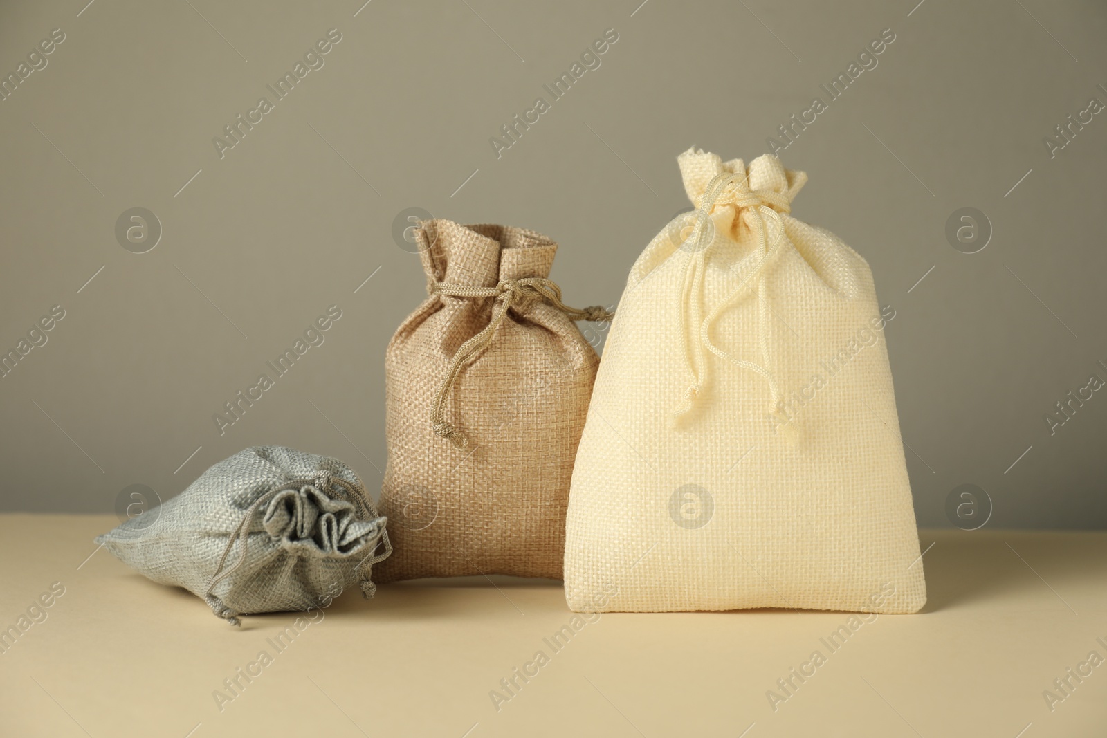 Photo of Burlap sacks on beige surface against gray background