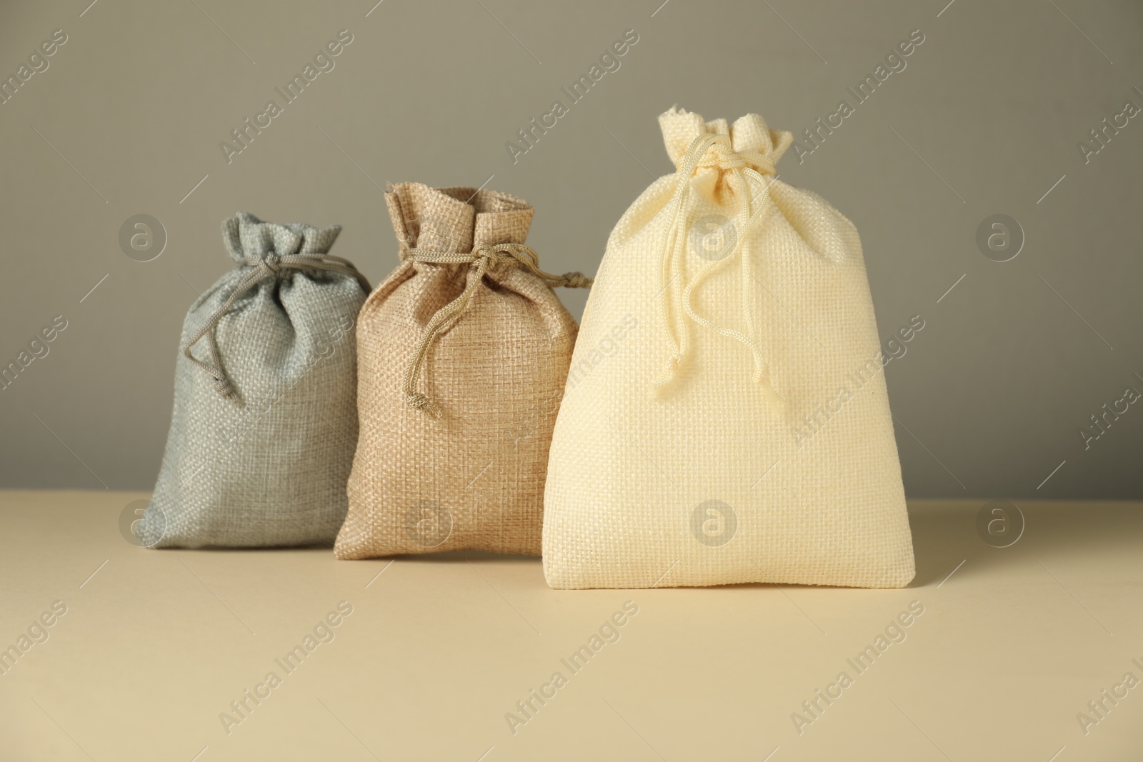 Photo of Burlap sacks on beige surface against gray background