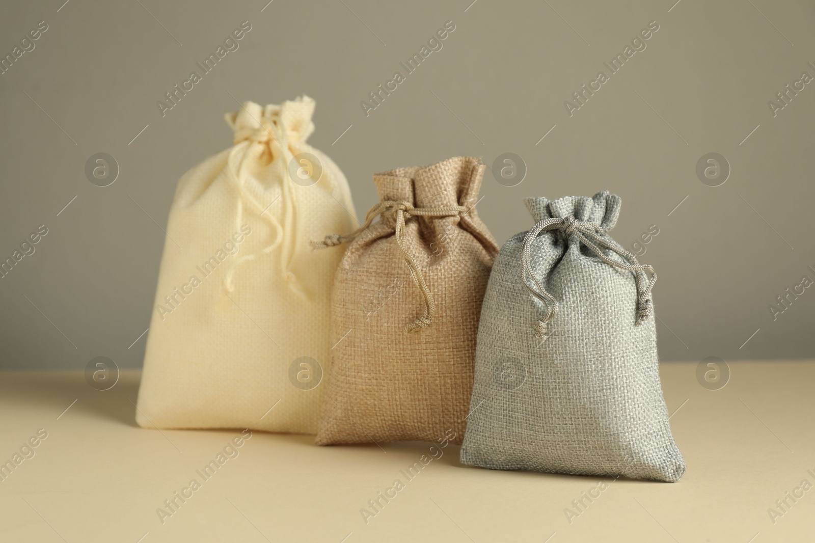 Photo of Burlap sacks on beige surface against gray background