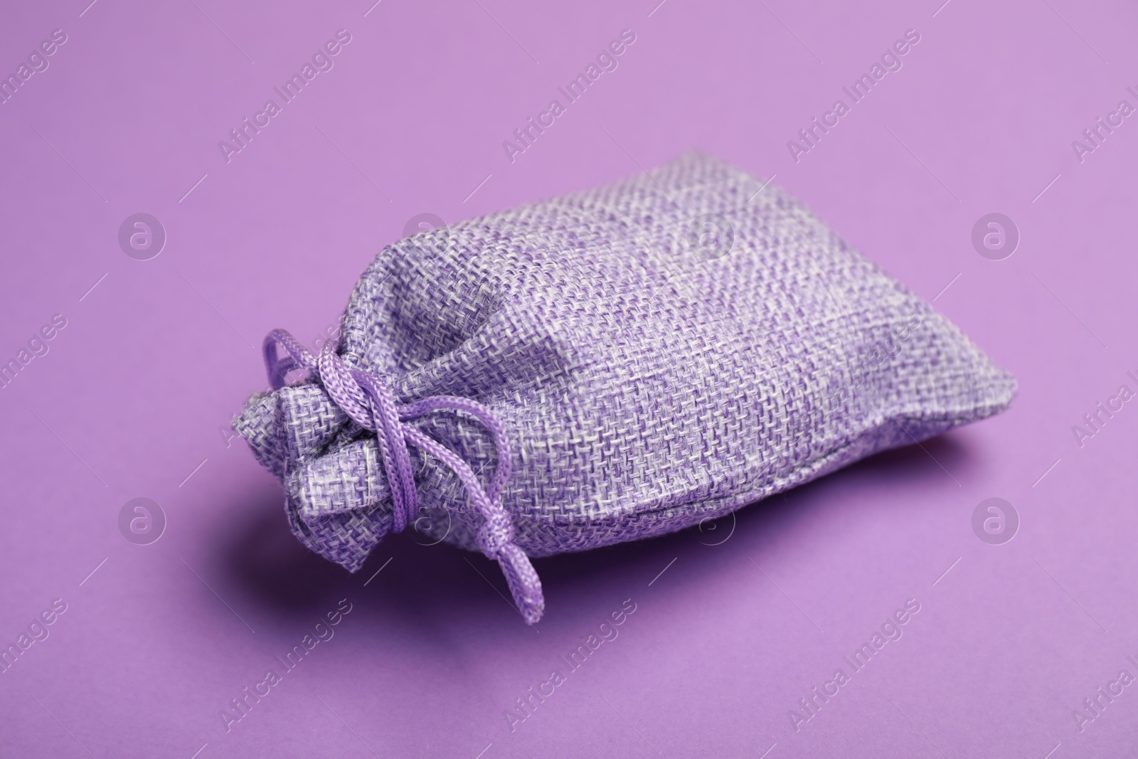 Photo of One burlap sack on violet background, closeup