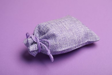 Photo of One burlap sack on violet background, closeup