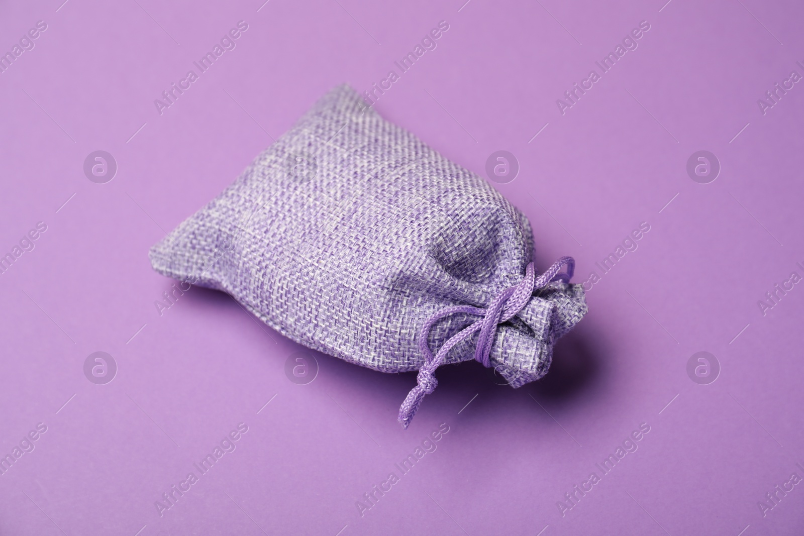 Photo of One burlap sack on violet background, closeup