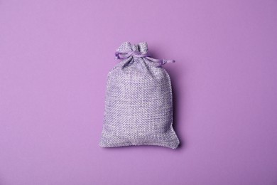 One burlap sack on violet background, top view