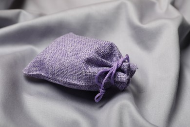 Photo of Violet burlap sack on gray fabric, closeup