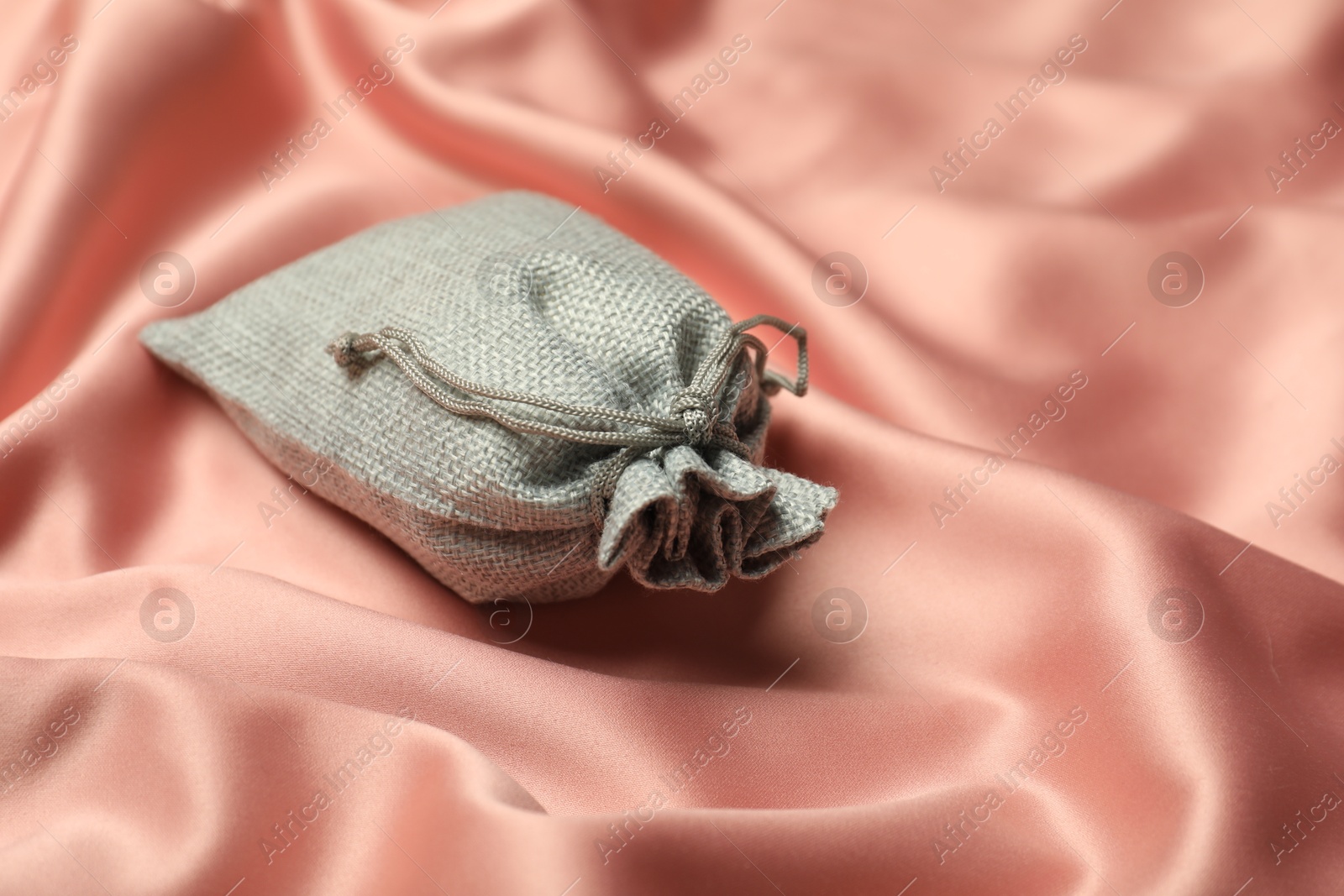 Photo of Gray burlap sack on coral fabric, closeup. Space for text