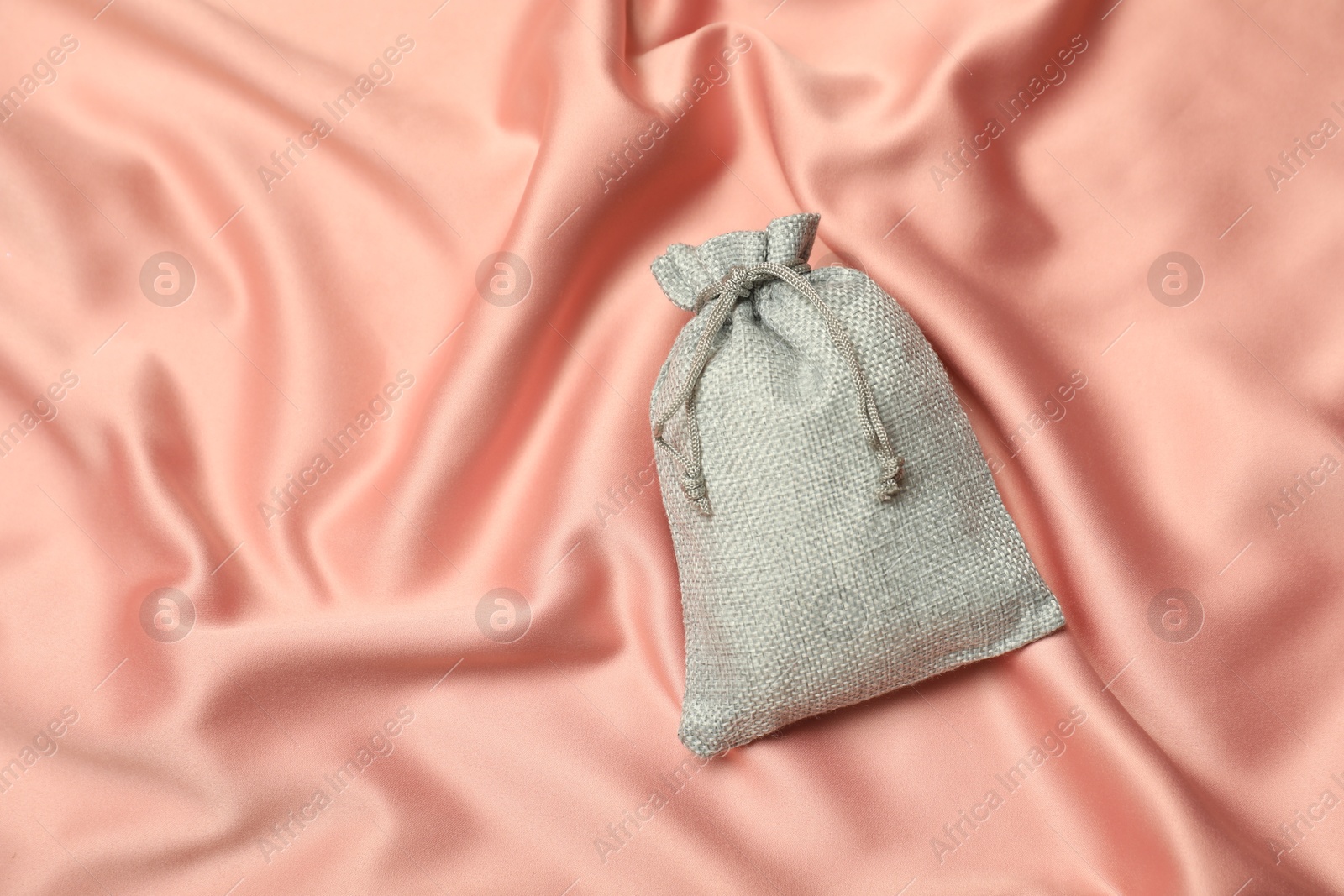 Photo of Gray burlap sack on coral fabric, top view. Space for text