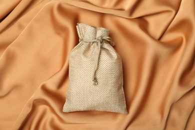 Beige burlap sack on orange fabric, top view