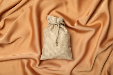 Photo of Beige burlap sack on orange fabric, top view