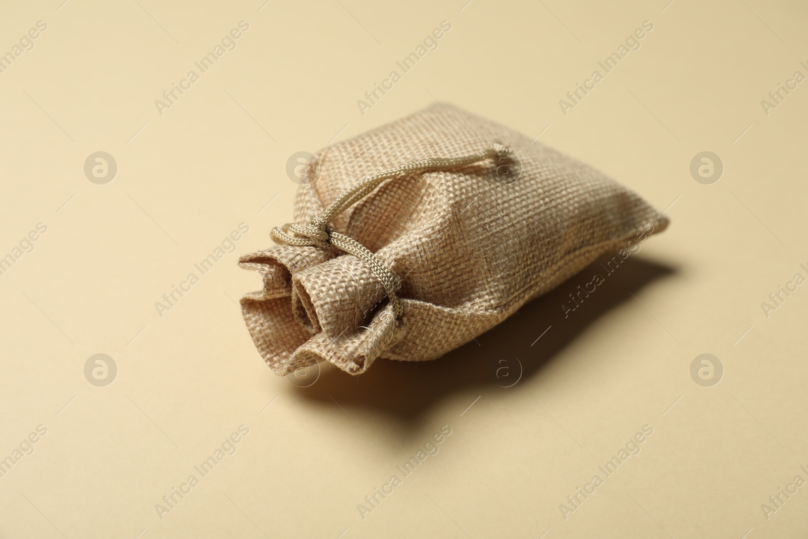 Photo of One burlap sack on beige background, closeup