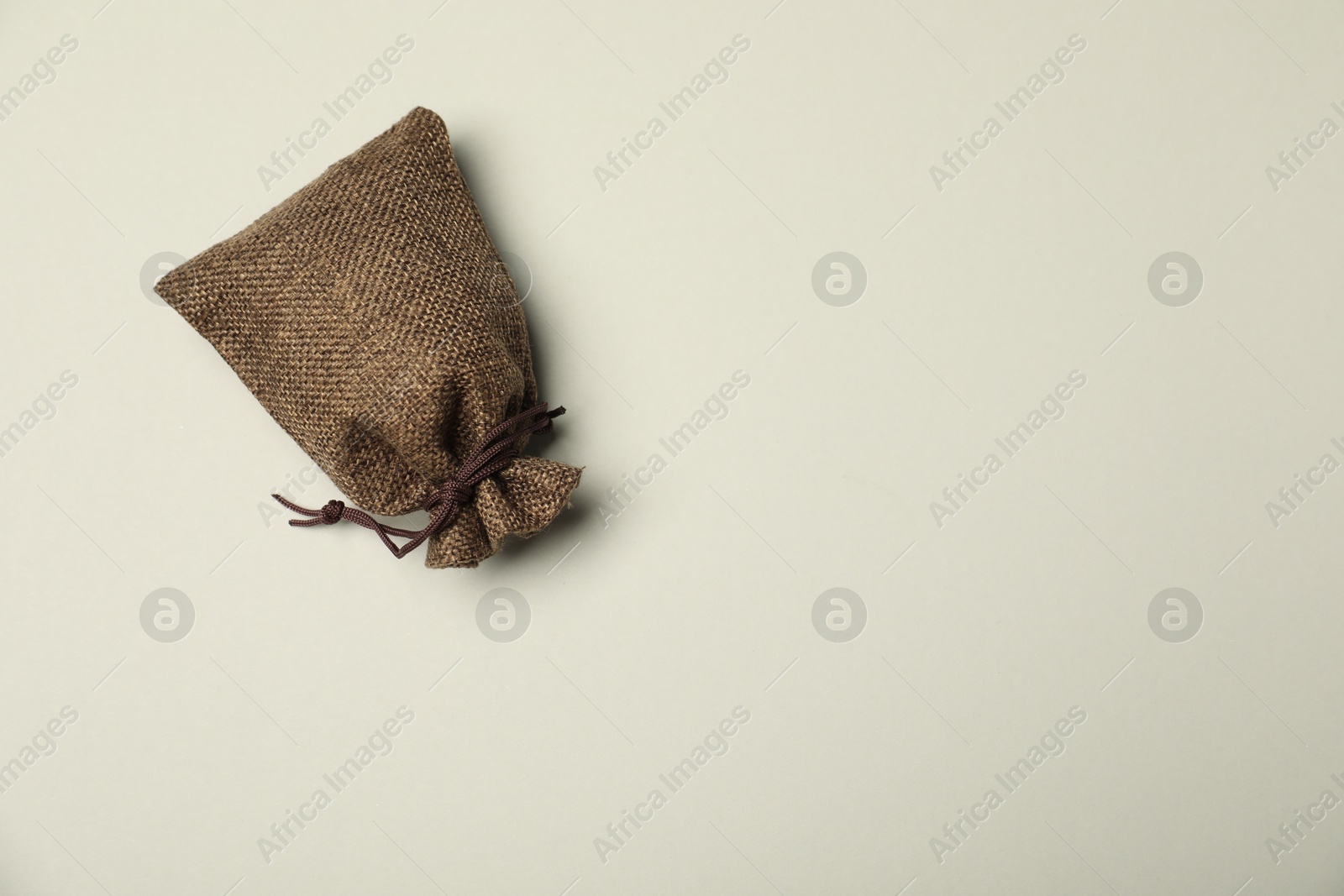 Photo of Brown burlap sack on light gray background, top view. Space for text