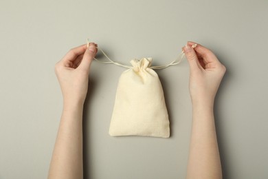 Photo of Woman with beige burlap sack on gray background, top view