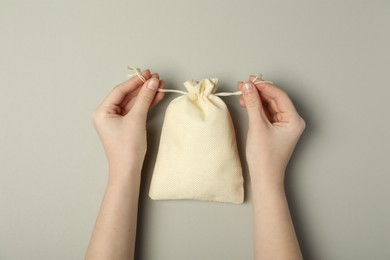 Photo of Woman with beige burlap sack on gray background, top view