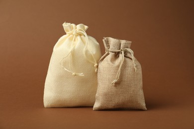 Photo of Two beige burlap sacks on brown background