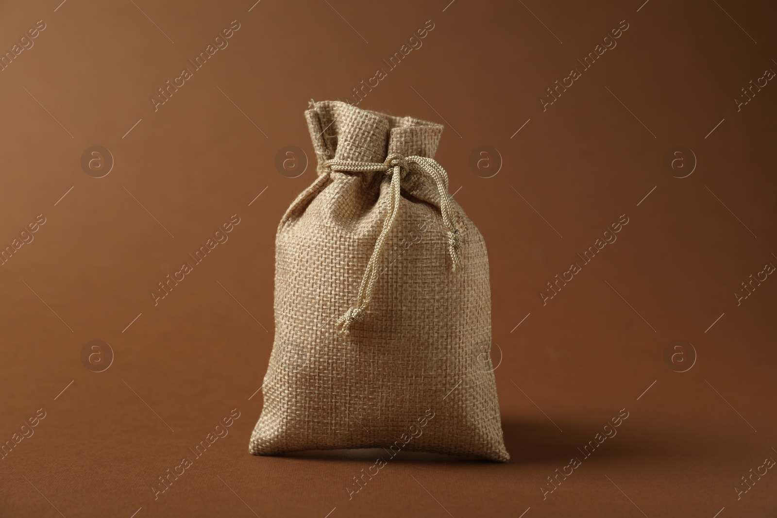 Photo of One beige burlap sack on brown background