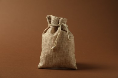 Photo of One beige burlap sack on brown background