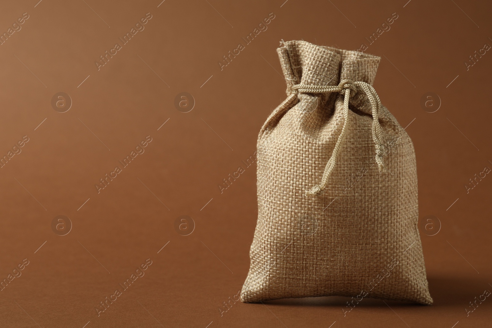 Photo of Burlap sack on brown background, space for text