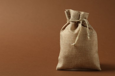 Burlap sack on brown background, space for text