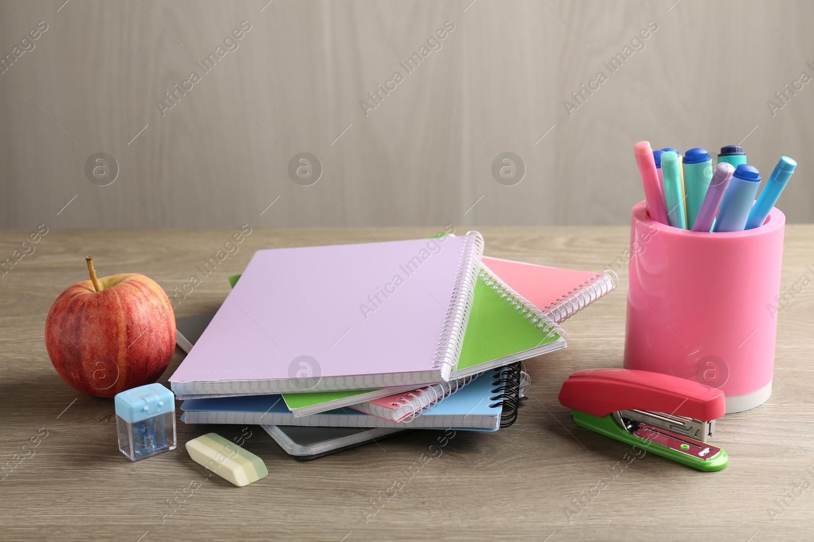 Photo of Doing homework. Notebooks, apple and stationery on wooden desk