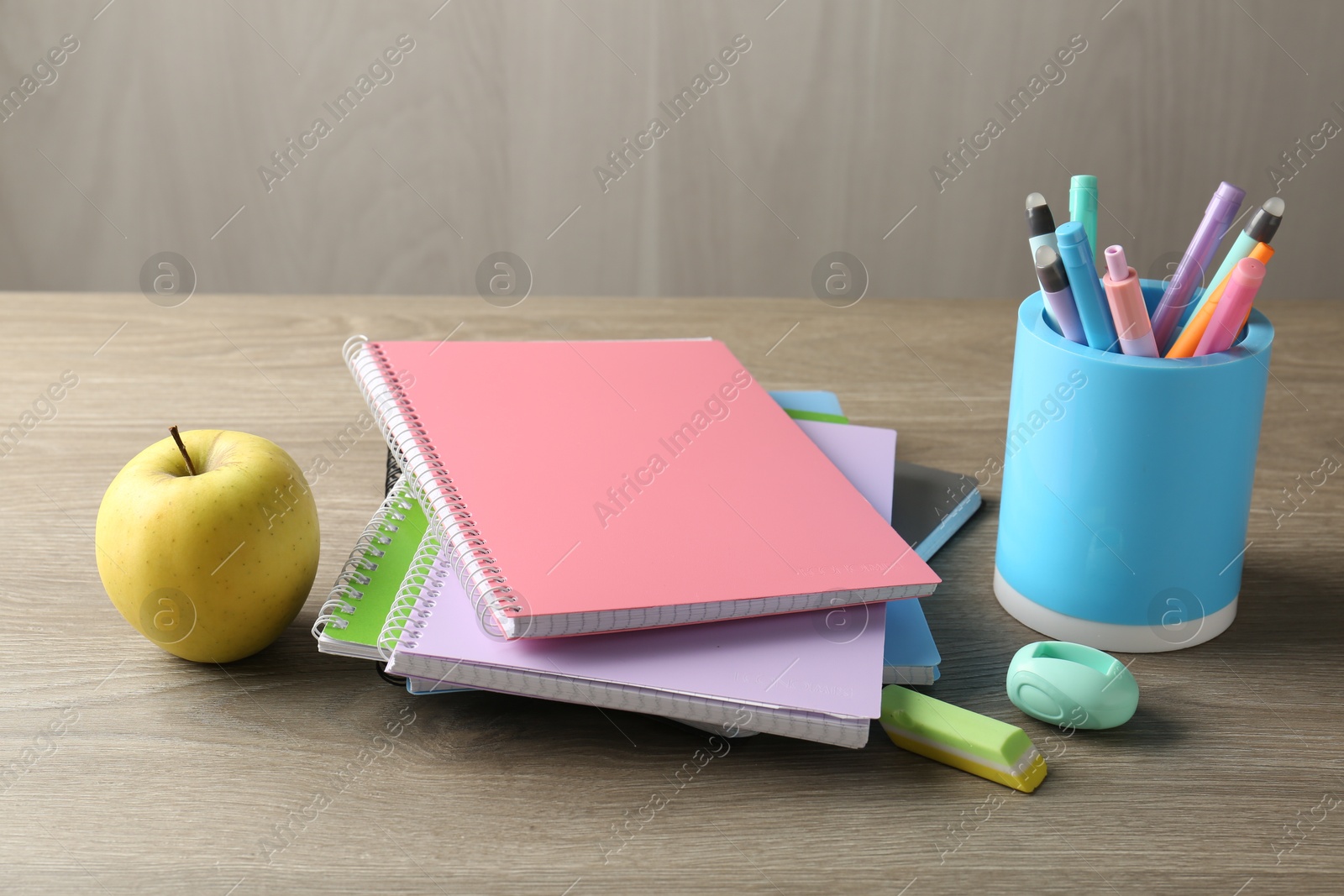 Photo of Doing homework. Notebooks, apple and stationery on wooden desk