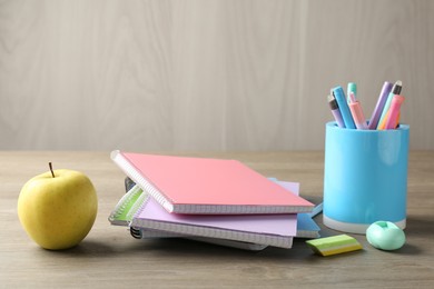 Photo of Doing homework. Notebooks, apple and stationery on wooden desk. Space for text