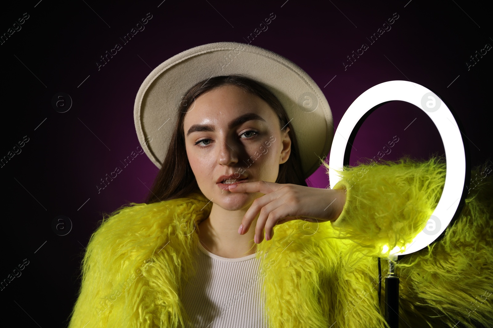 Photo of Stylish woman with ring lamp on dark purple background