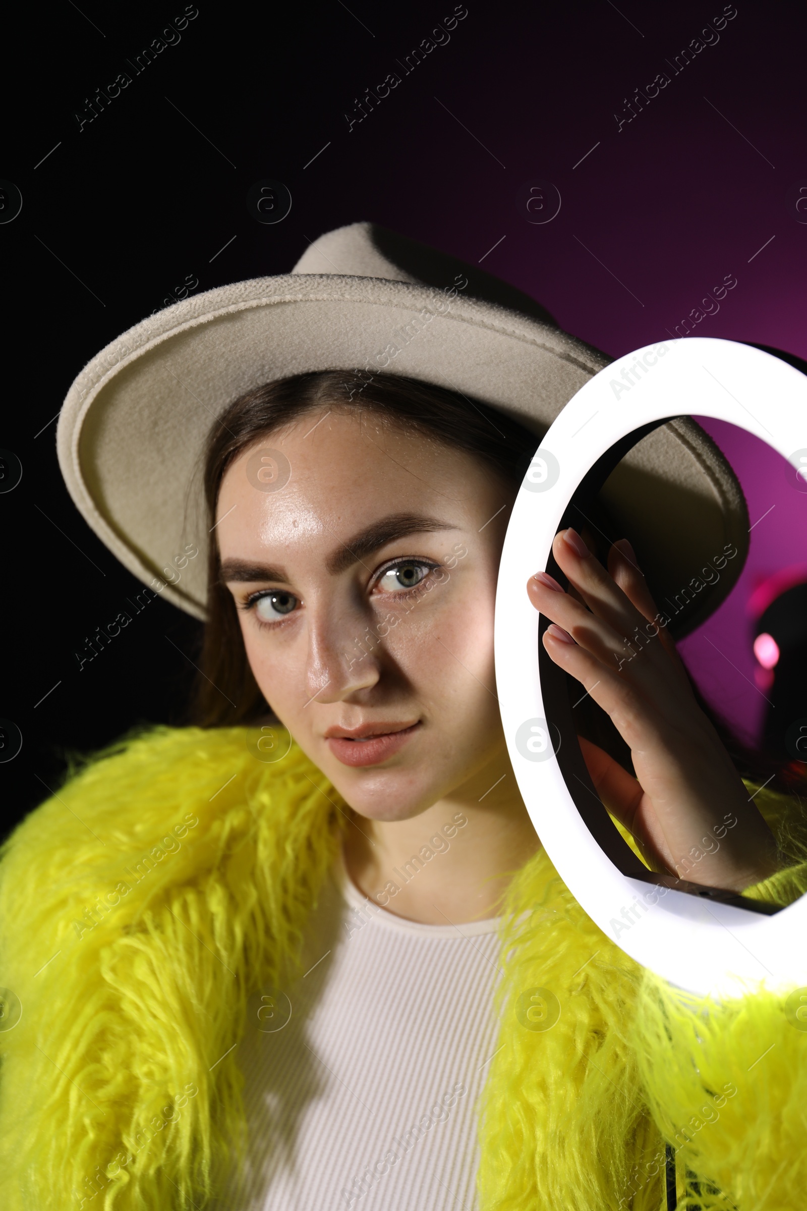 Photo of Stylish woman with ring lamp on dark purple background