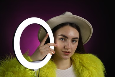 Photo of Stylish woman with ring lamp on dark purple background