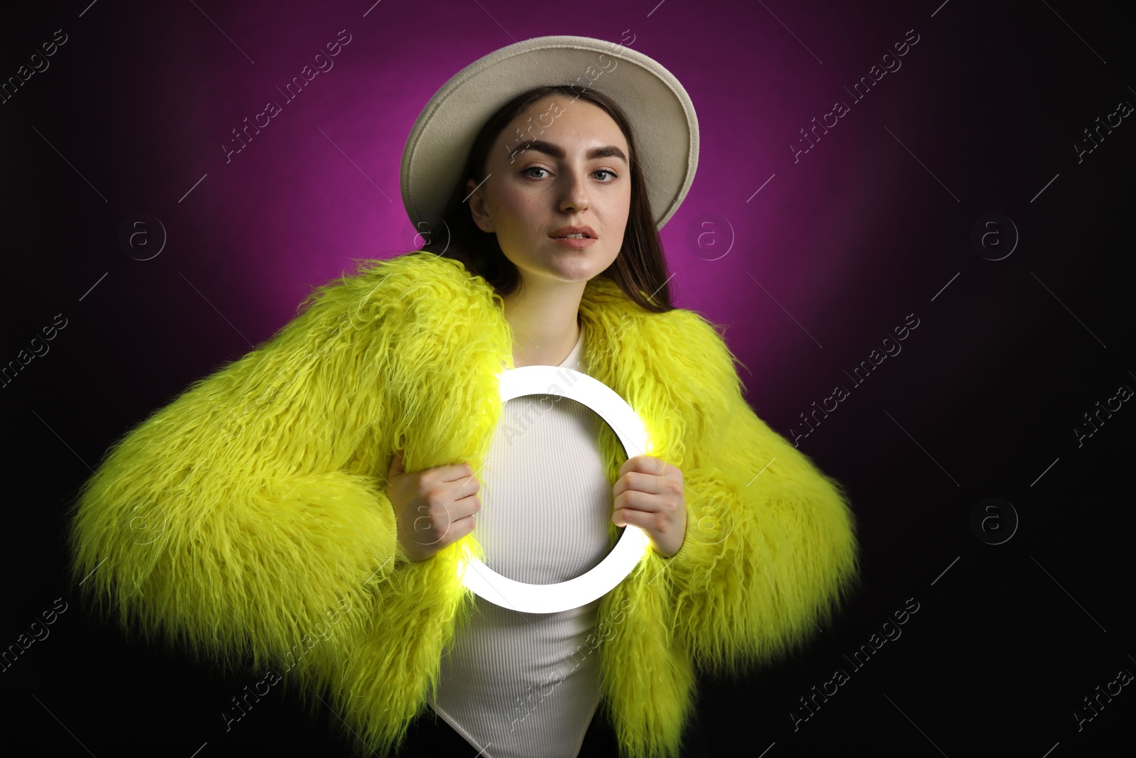 Photo of Stylish woman with ring lamp on dark purple background, space for text