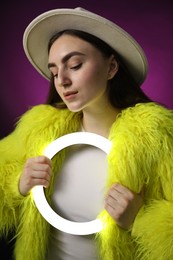 Photo of Stylish woman with ring lamp on dark purple background