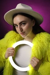 Photo of Stylish woman with ring lamp on dark purple background