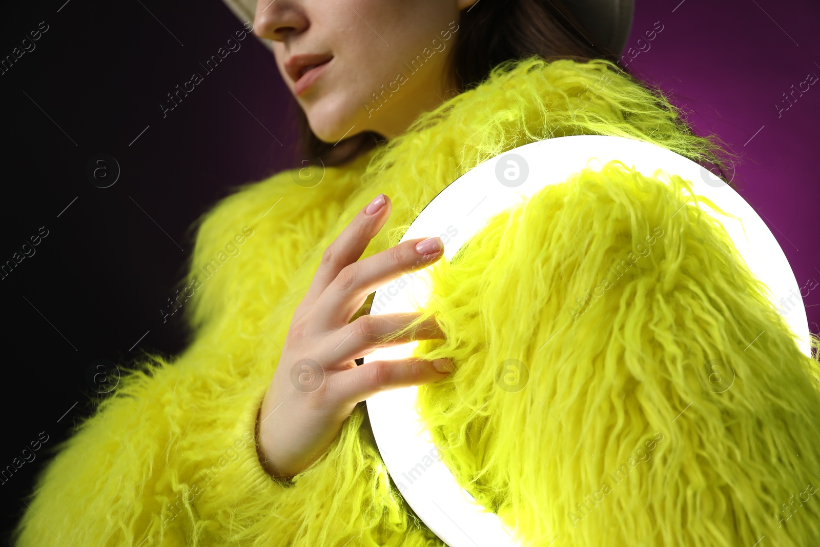 Photo of Stylish woman with ring lamp on dark purple background, closeup