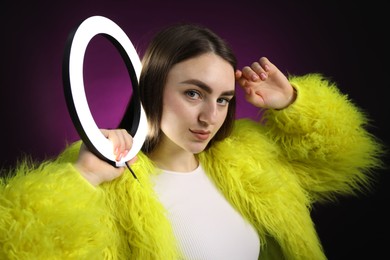 Photo of Stylish woman with ring lamp on dark purple background