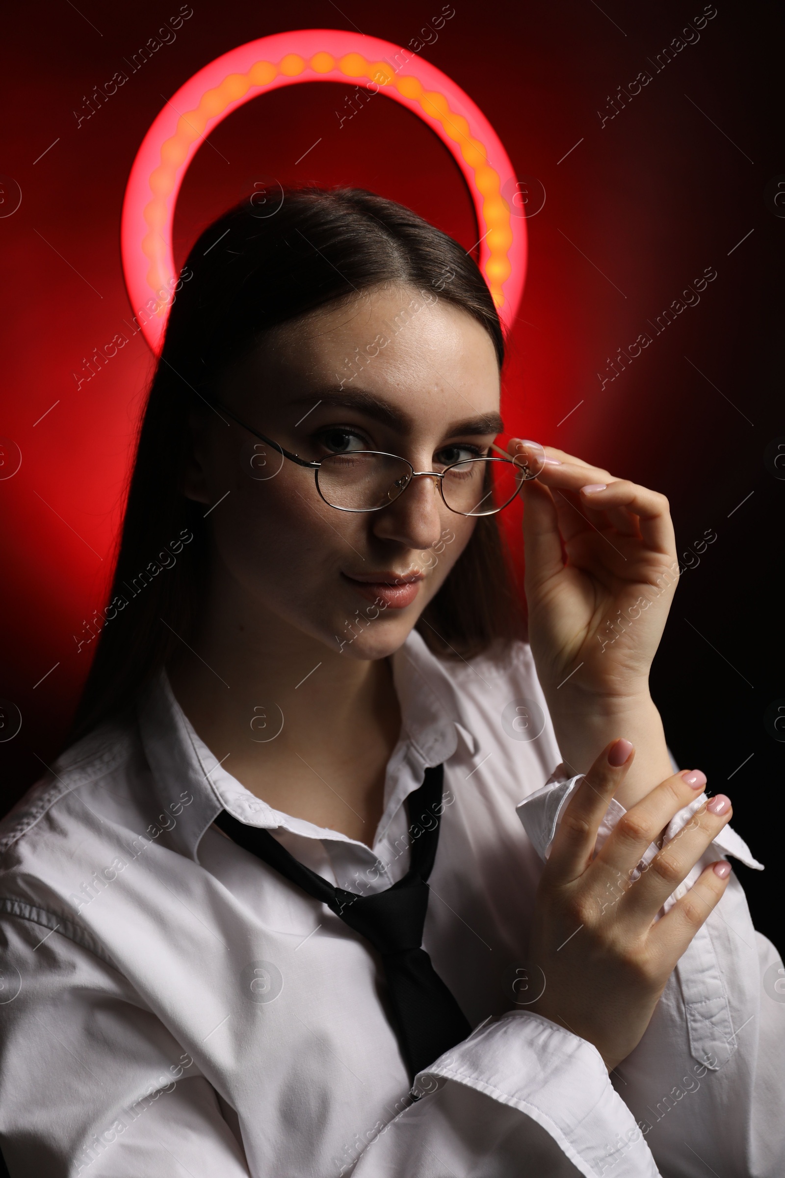 Photo of Beautiful woman with ring lamp wearing glasses on dark red background