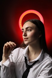 Beautiful woman with ring lamp and glasses on dark red background