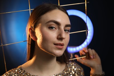 Photo of Beautiful woman with grid and ring lamp on dark blue background