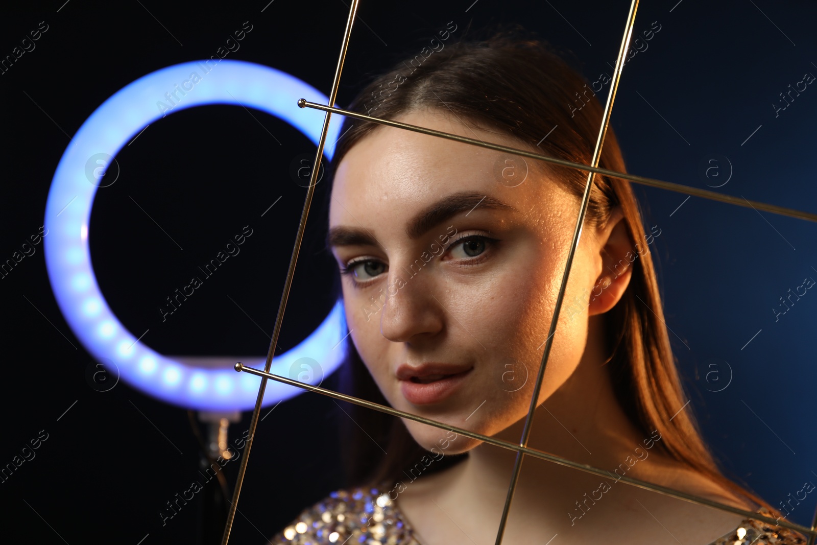 Photo of Beautiful woman with grid and ring lamp on dark blue background