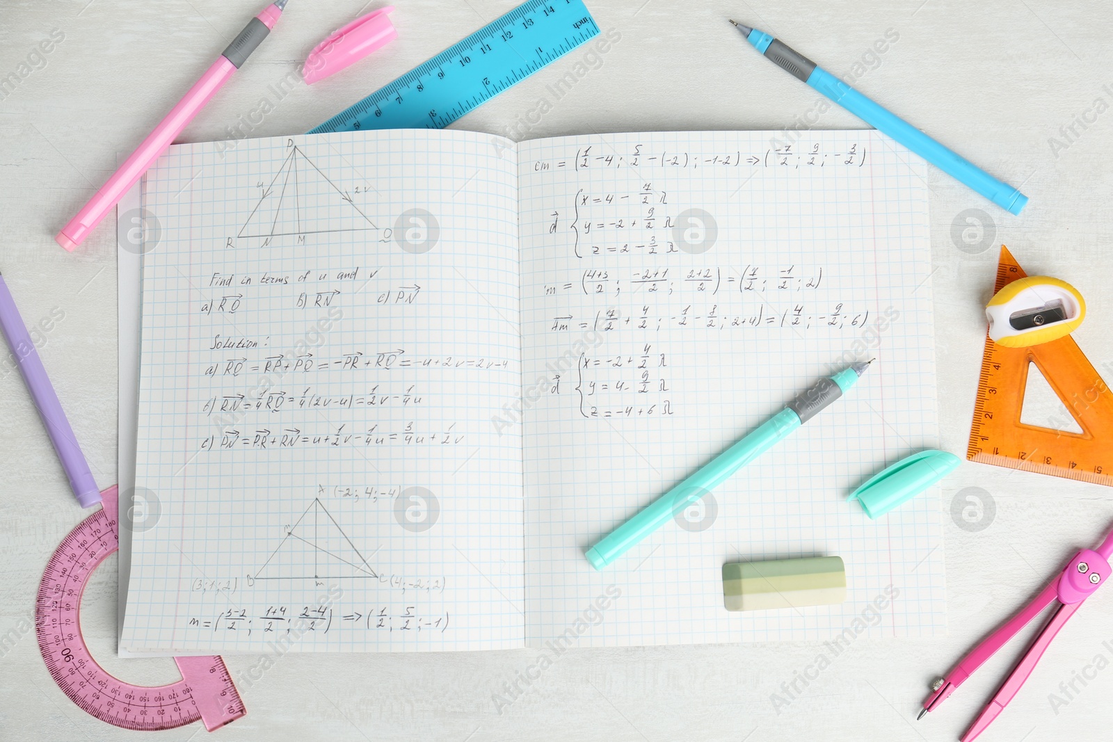 Photo of Doing homework. Notebook with math assignment and stationery on white desk, flat lay