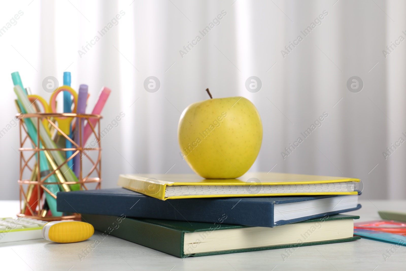 Photo of Doing homework. Notebooks, apple and stationery on white desk