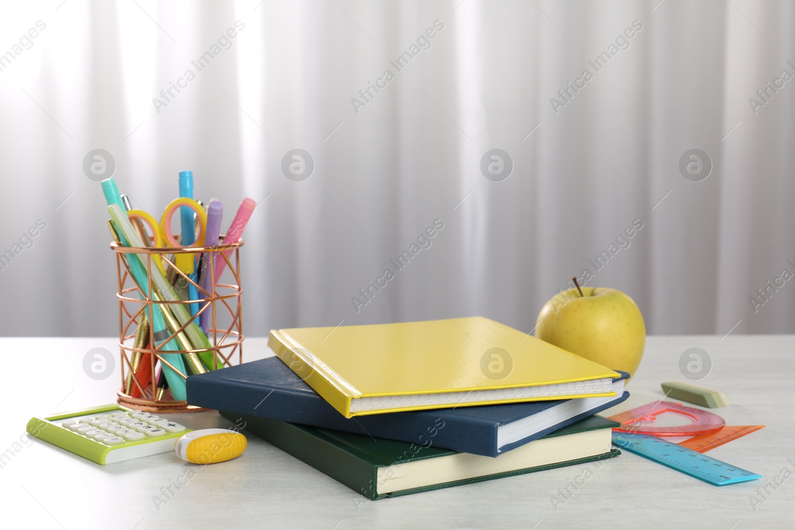 Photo of Doing homework. Notebooks, apple and stationery on white desk. Space for text