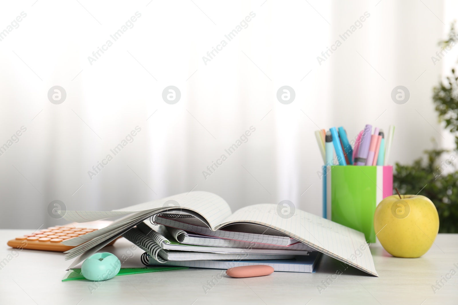 Photo of Doing homework. Notebook with assignment, apple and stationery on white desk. Space for text