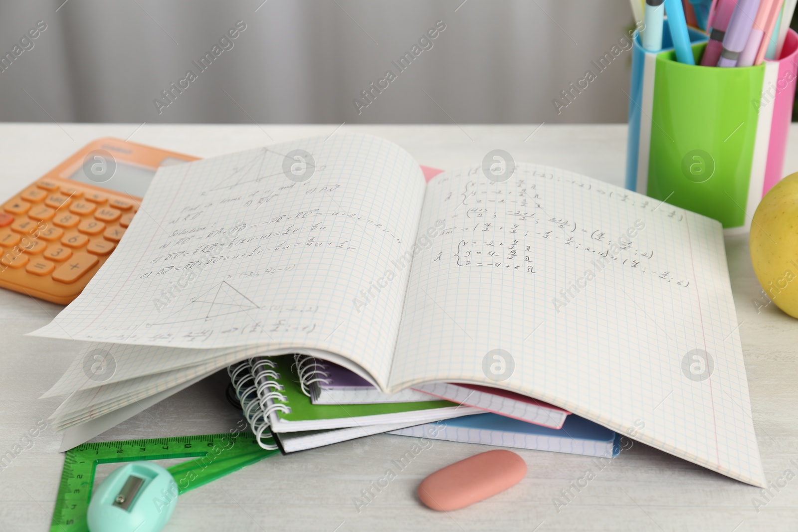 Photo of Doing homework. Notebook with assignment and stationery on white desk, closeup