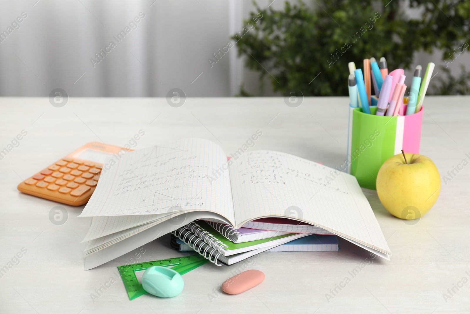 Photo of Doing homework. Notebook with math assignment, apple and stationery on white desk. Space for text