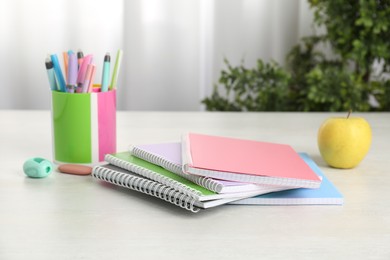 Photo of Doing homework. Notebooks, apple and stationery on white desk. Space for text