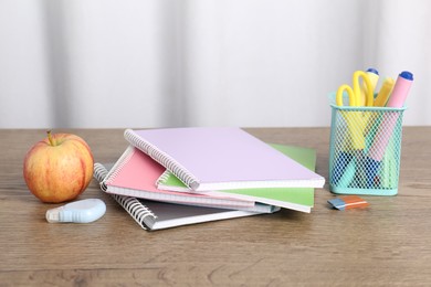 Photo of Doing homework. Notebooks, apple and stationery on wooden desk