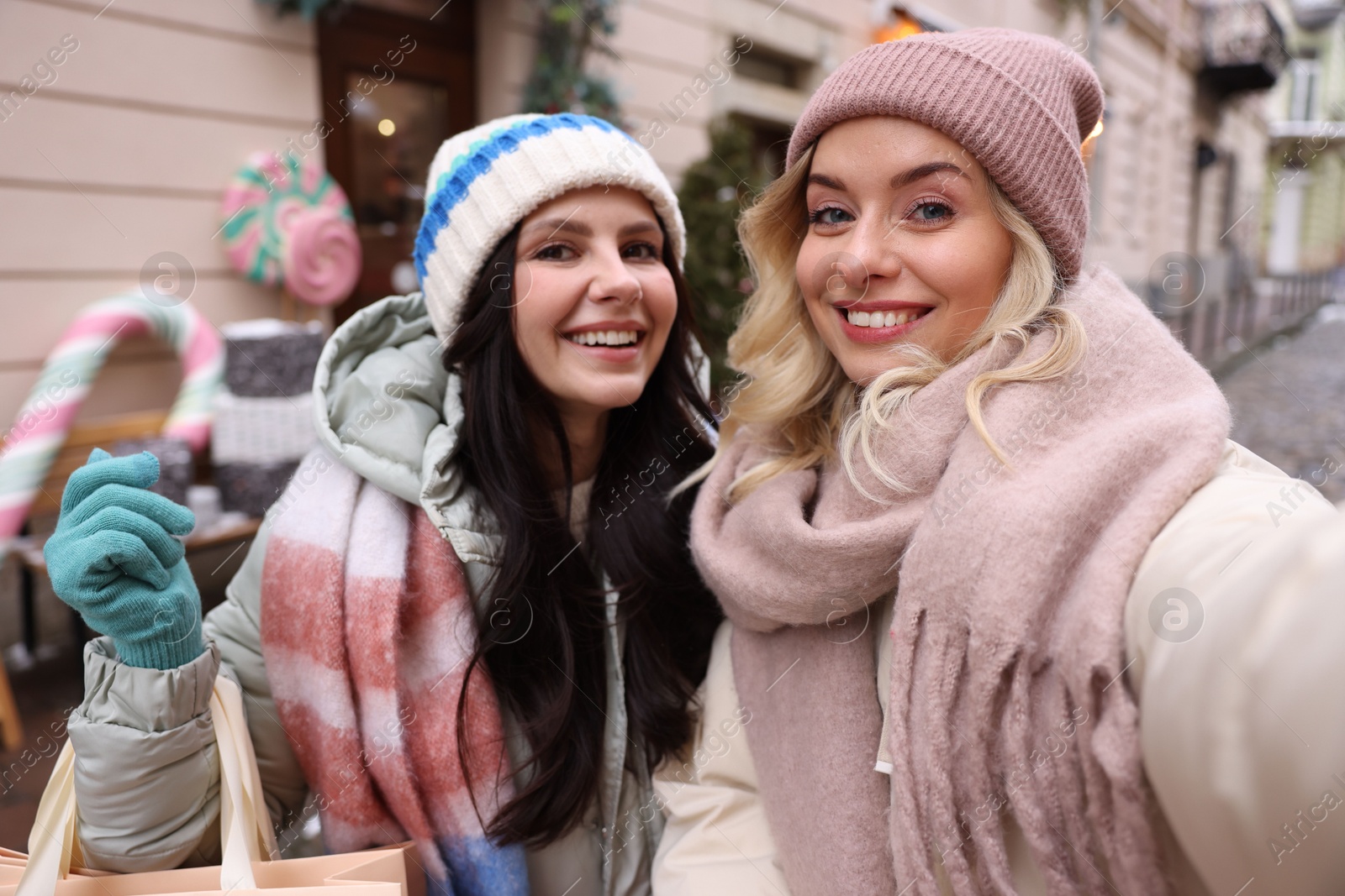 Photo of Happy friends taking selfie on city street. Christmas season