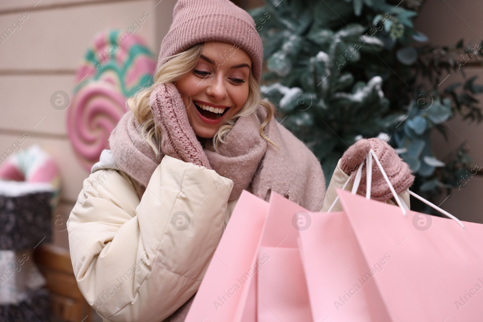 Photo of Happy woman with paper bags near shop outdoors. Christmas season