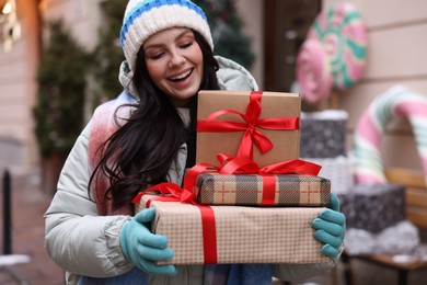 Photo of Happy woman with Christmas gifts on city street