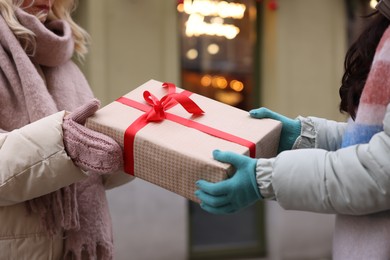 Photo of Friends with Christmas gift on city street, closeup