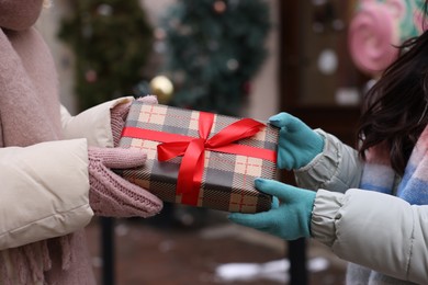 Photo of Friends with Christmas gift on city street, closeup