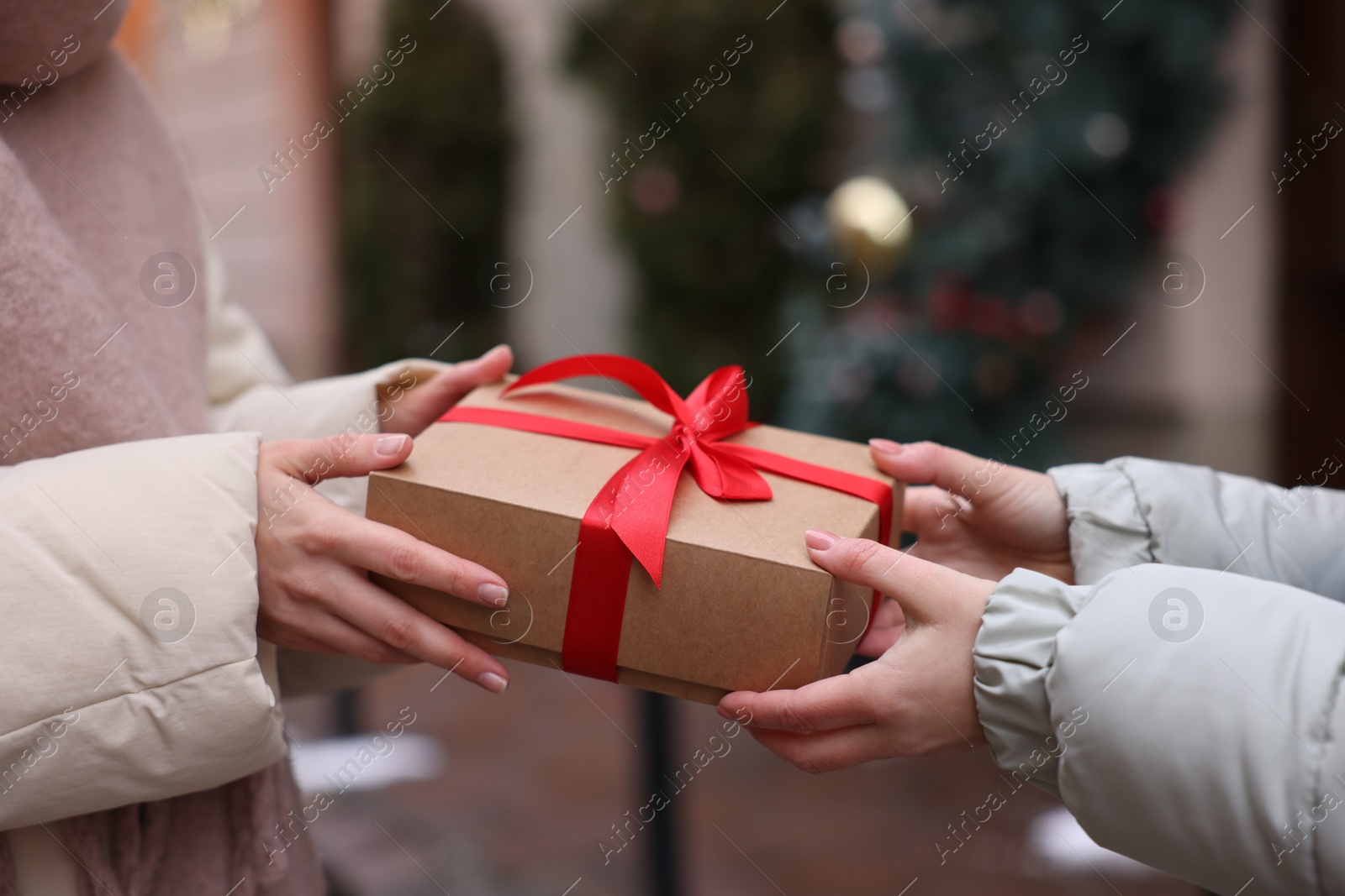 Photo of Friends with Christmas gift on city street, closeup